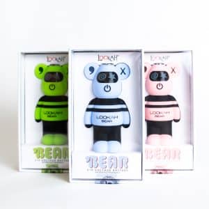 Three boxed Lookah Bear Dab Pen Batteries are shown in green, blue, and pink, each with a bear-shaped design featuring X eyes and spiral cheeks.