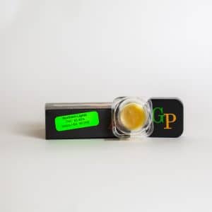 A small container of Green Crack Sugar Wax - Label No.420 - 1g rests atop a black box, featuring a green sticker.