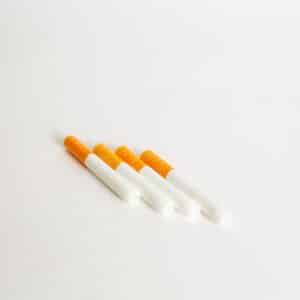 Four Quartz Bat cigarette tubes with orange filters are arranged diagonally on a plain white surface.